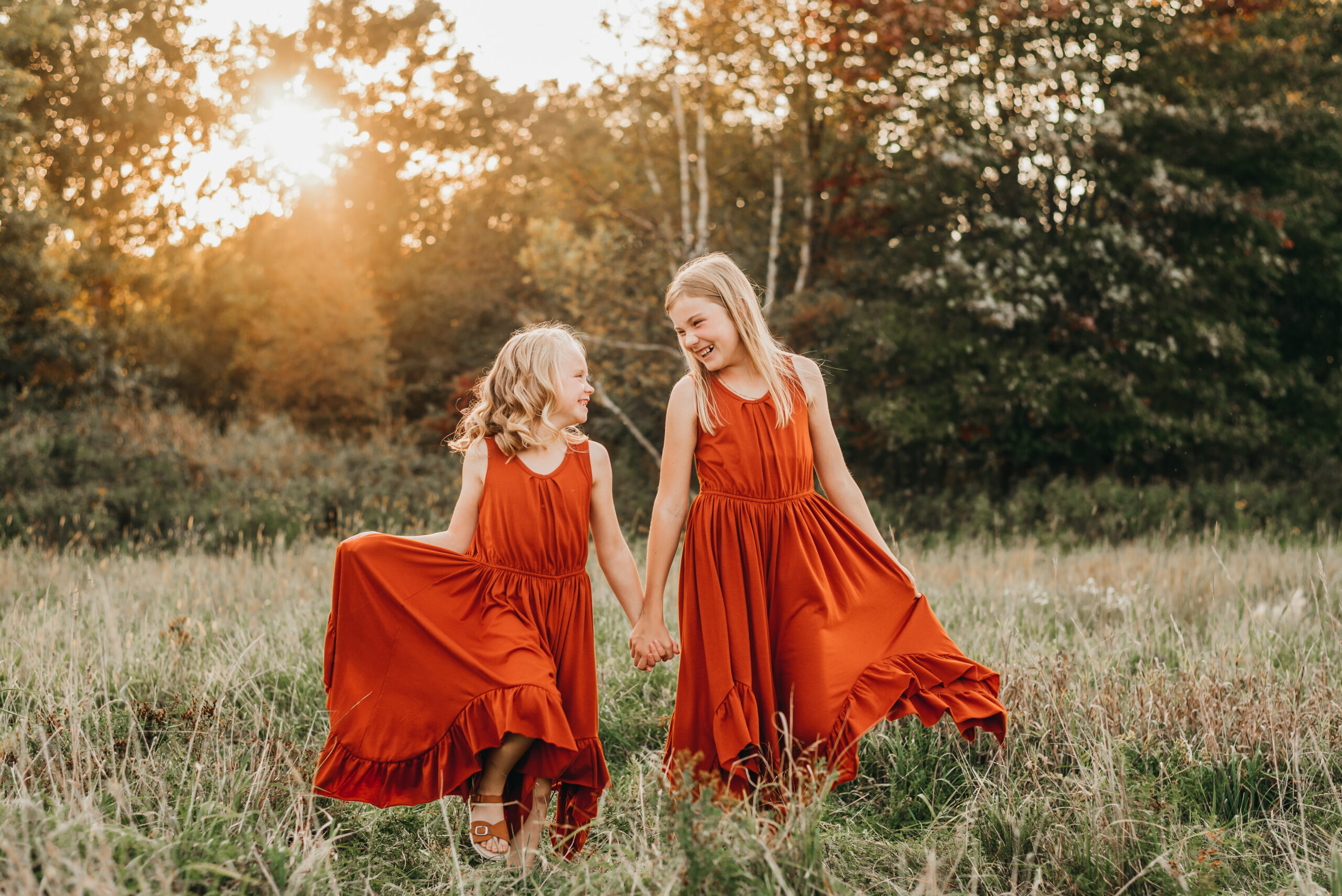 Two young girls walking hand in hand during a golden hour portrait session with sharp focus and natural light.